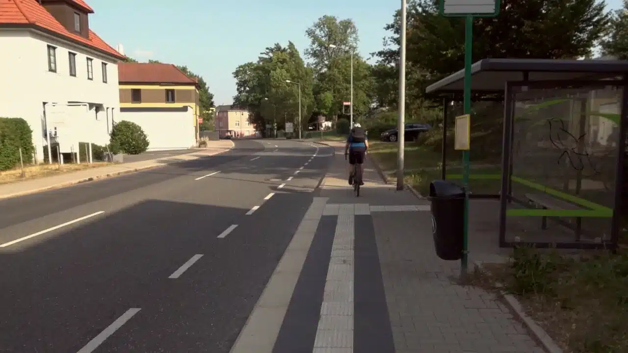 Ein Junge fährt auf einem Fahrrad an einer Straße ausgehend von einer Bushaltestelle aus