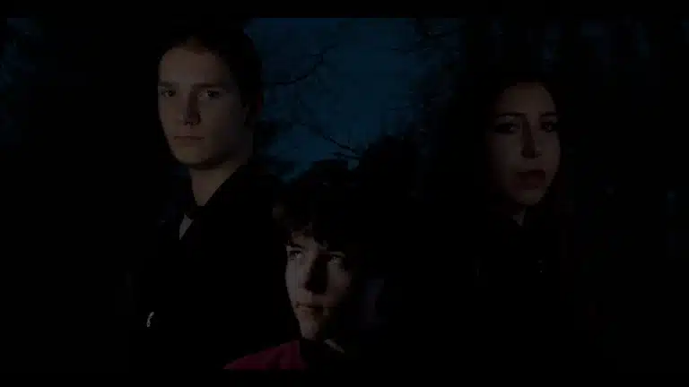 Drei Personen stehen vor einem dunklen Hintergrund.