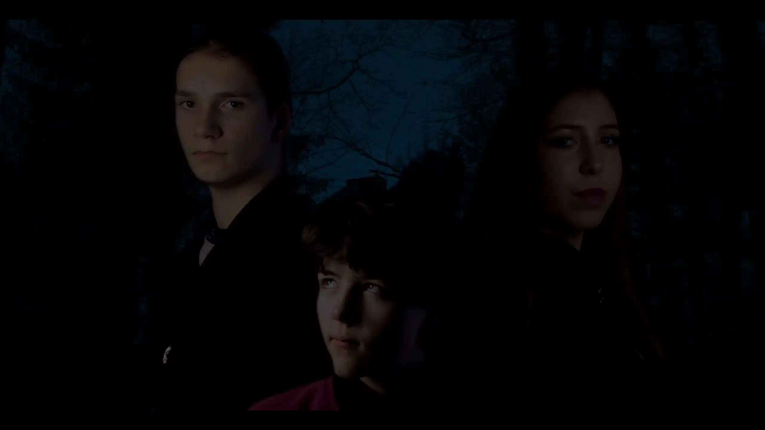 Drei Personen stehen vor einem dunklen Hintergrund.